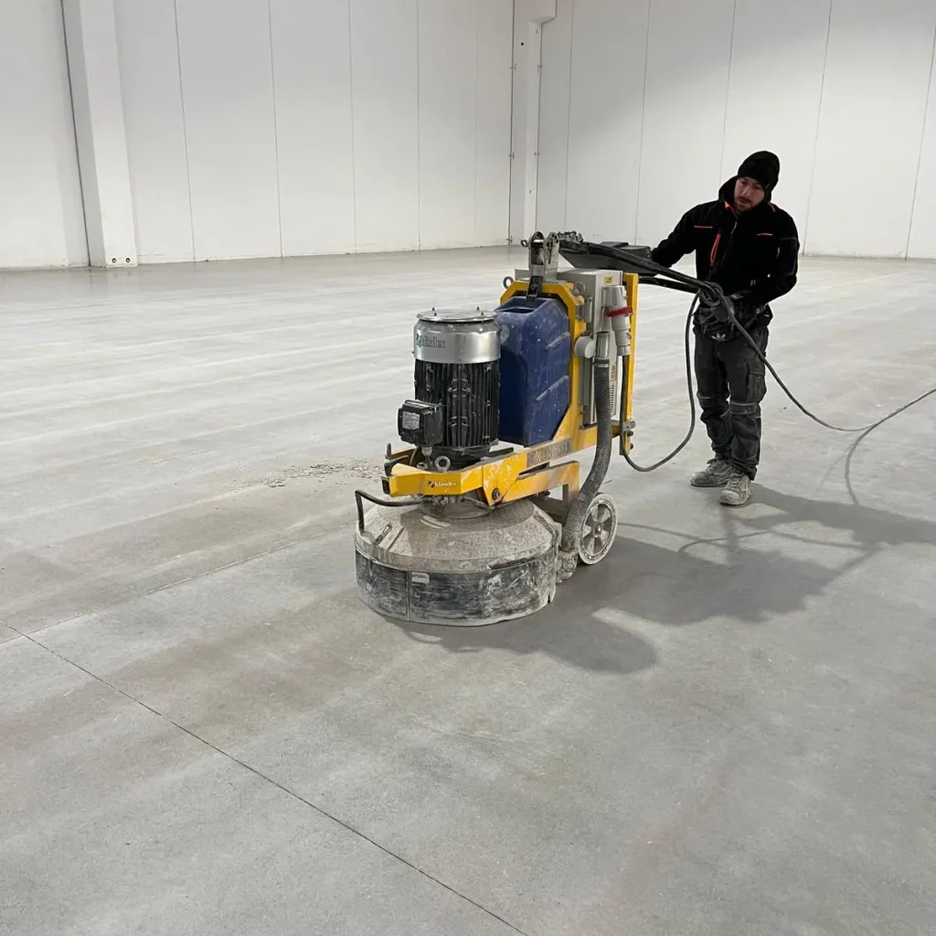 Operatore Cleaner Pro durante la levigatura di un pavimento in cemento